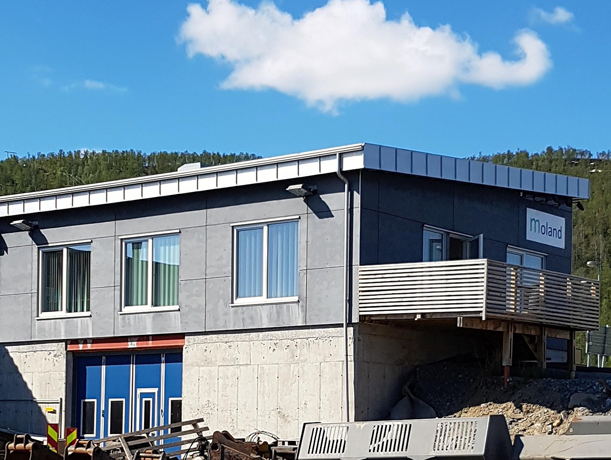 Bygg i to etasjer med balkong og blå inngangsparti
